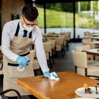 waiter-with-protective-face-mask-disinfecting-tables-cafe-due-coronavi